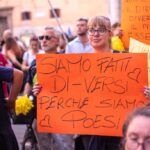 una giovane manifestante con un cartello arancione con scritto: siamo fatti di-versi perché siamo poesia